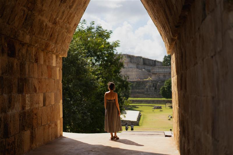 A woman in a dress standing in an archway at Uxmal, Mexico.