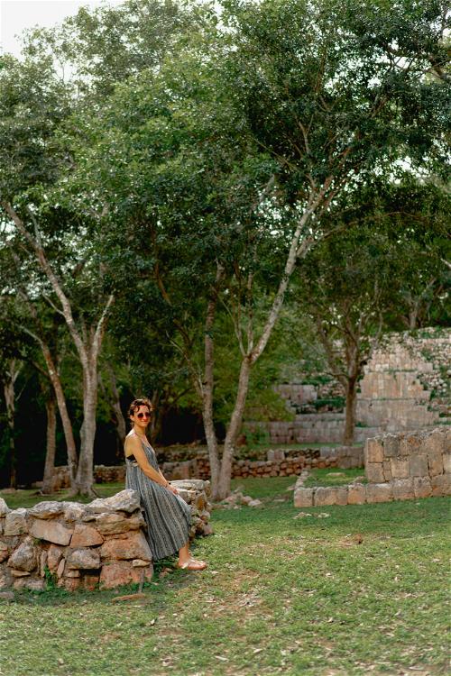 A woman sitting on a stone wall in Uxmal, Mexico.