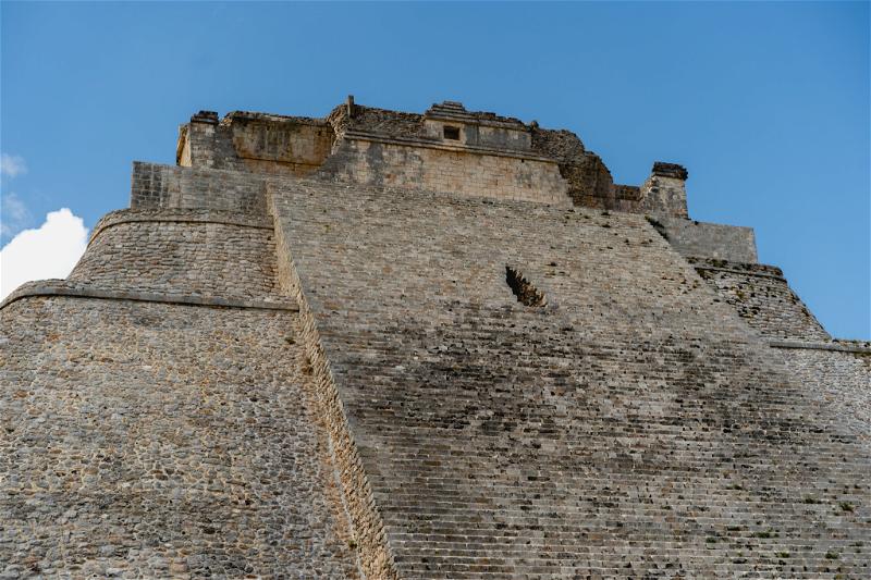 The top of the Uxmal building is embraced by a blue sky.