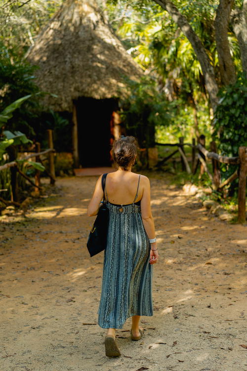 A woman walking near a hut in Uxmal, Mexico.