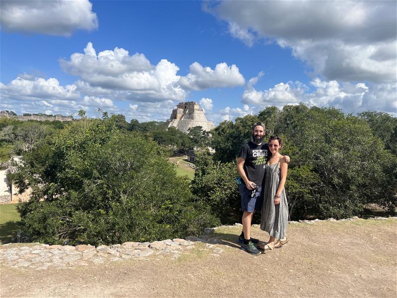 A man and woman posing for a photo in front of an ancient ruin in Uxmal, Mexico.