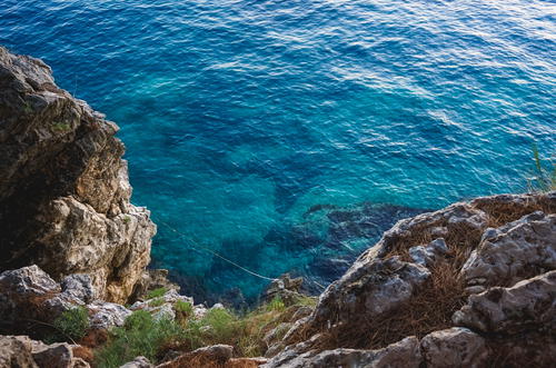 A man standing on top of a cliff next to the ocean