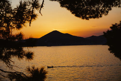 A boat floating on top of a lake at sunset