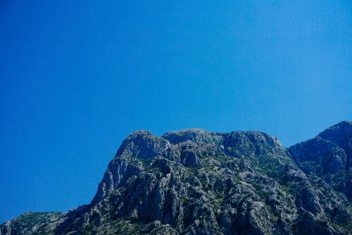 A very tall mountain with a clear blue sky in Budva
