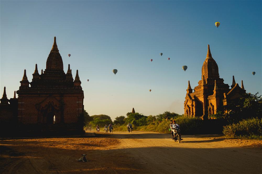 A group of people riding motorcycles through the scenic dirt roads of Myanmar's ancient city, Bagan.