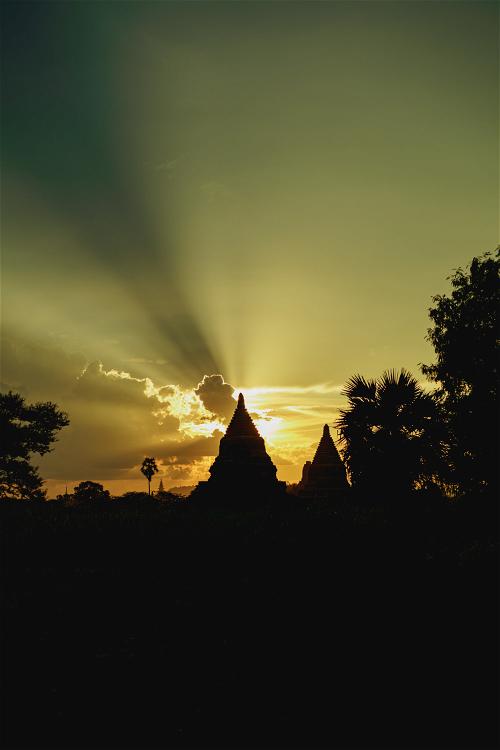 Sun coming through clouds near a stupa at sunset Bagan Myanmar Burma