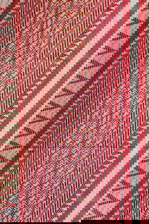 A red and white striped cloth, reminiscent of Indian and Myanmar (Burma) textiles, decorates the wall.