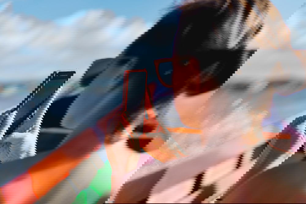 Girl taking photos on a cell phone on a sunny day during a boat tour of Inle Lake Myanmar