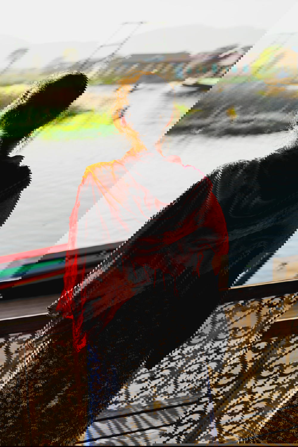 Girl wearing a red sarong looking at the waterway roads of the lake communities around Inle Lake Myanmar