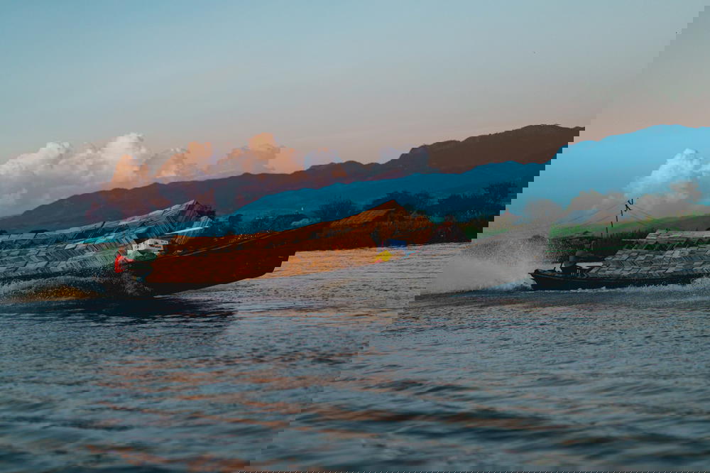 Two men drive a motorized motorboat full of wooden boxes along the waterways of Inle Lake Myanmar