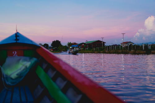 A boat is traveling down Burma's Inle Lake at sunset.