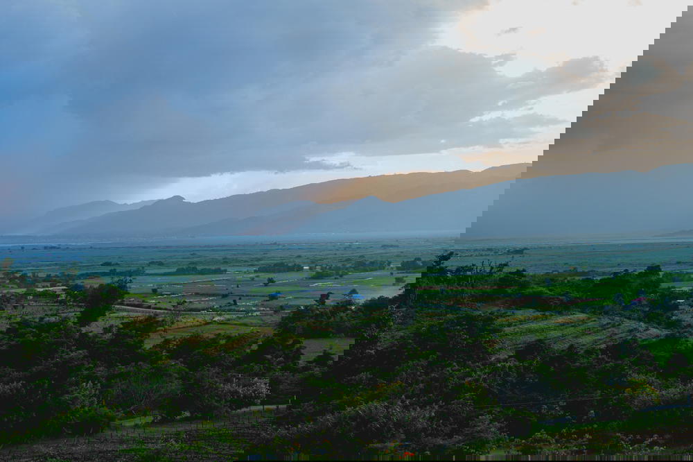 Rain clouds passing over mountains with farmland and fields below as seen from a hilltop near Inle Lake Myanmar