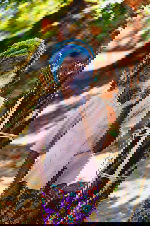 An old woman smoking a cigarette in front of a brick wall near Inle Lake, Myanmar.