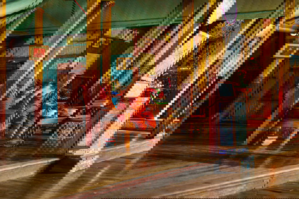 Male Buddhist monk sits in orange robes in an office at the Jumping Cat Monastery in Inle Lake Myanmar