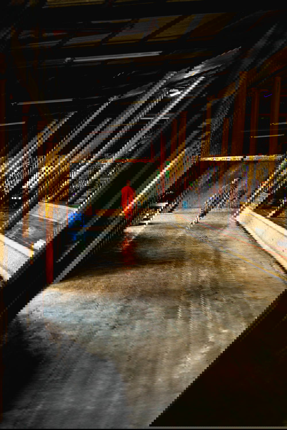 Buddhist monk in robes walking down a long hallway at Jumping Cat Monastery in Inle Lake Myanmar