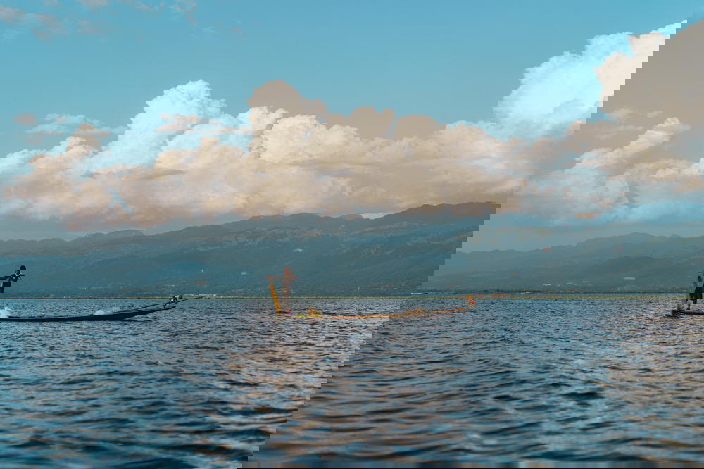 Young Burmese boy fishing from a wooden boat on a sunny clear day at Inle Lake Myanmar