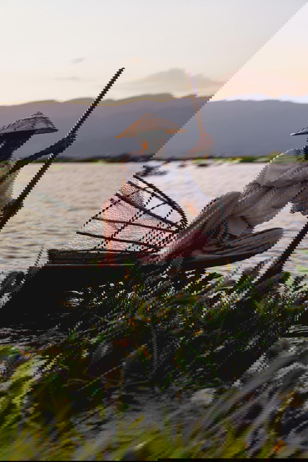 Inle Lake dancing fisherman sitting in a traditional Burmese fishing boat smiling at sunset in Myanmar
