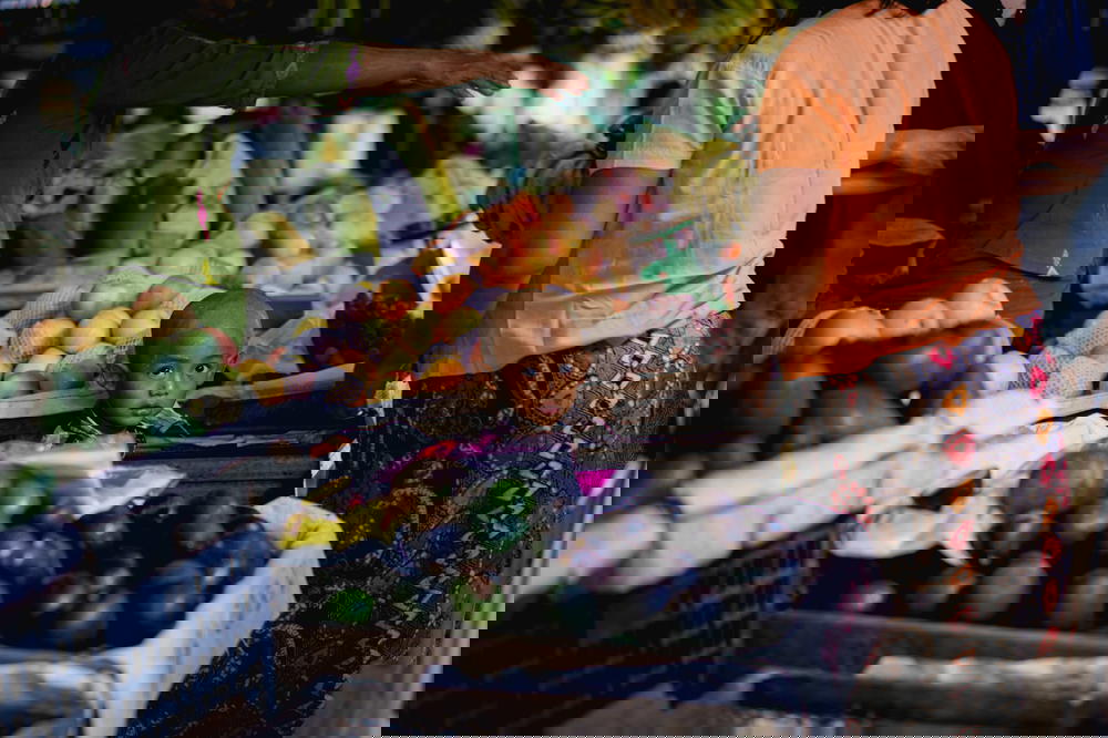Young Burmese boy with shaved head standing among boxes of food at the village market in Nyaungshwe Myanmar