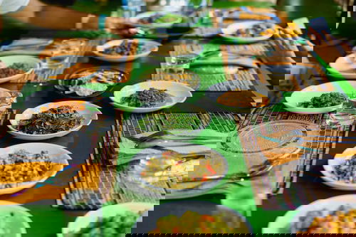 Green wooden table with place settings and white plates of Burmese salads