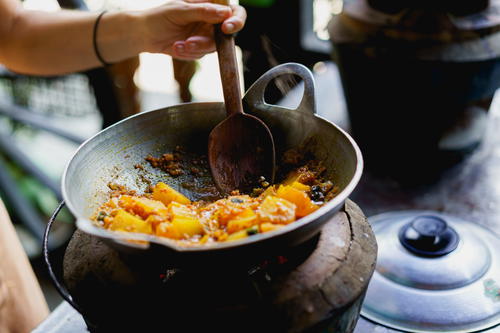 A woman pouring food into a pan on Inle Lake in Myanmar (Burma).