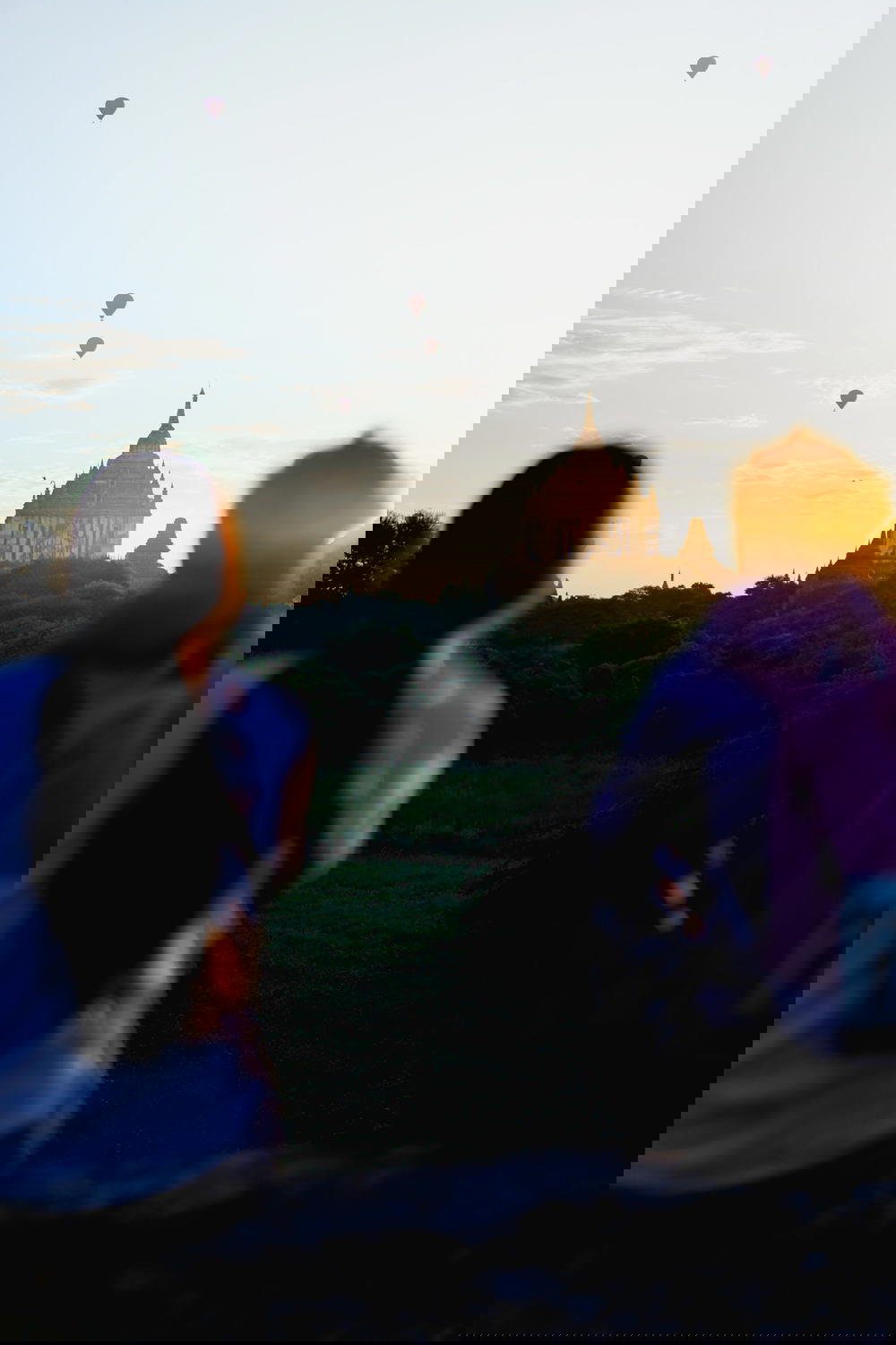 Man and woman look into the distance as the sun comes up from a viewing deck for sunrise at Bagan Myanmar