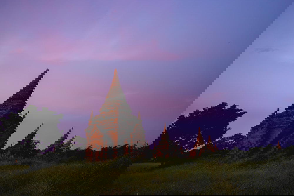 Pink and purple sunset sky with a view of several red stone pagodas in Bagan Myanmar