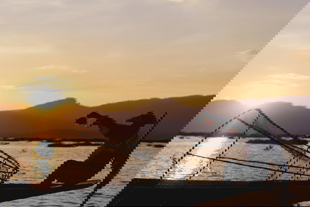 Burmese dancing fisherman of Inle Lake Myanmar holds up a fish for a photo in his boat at sunset