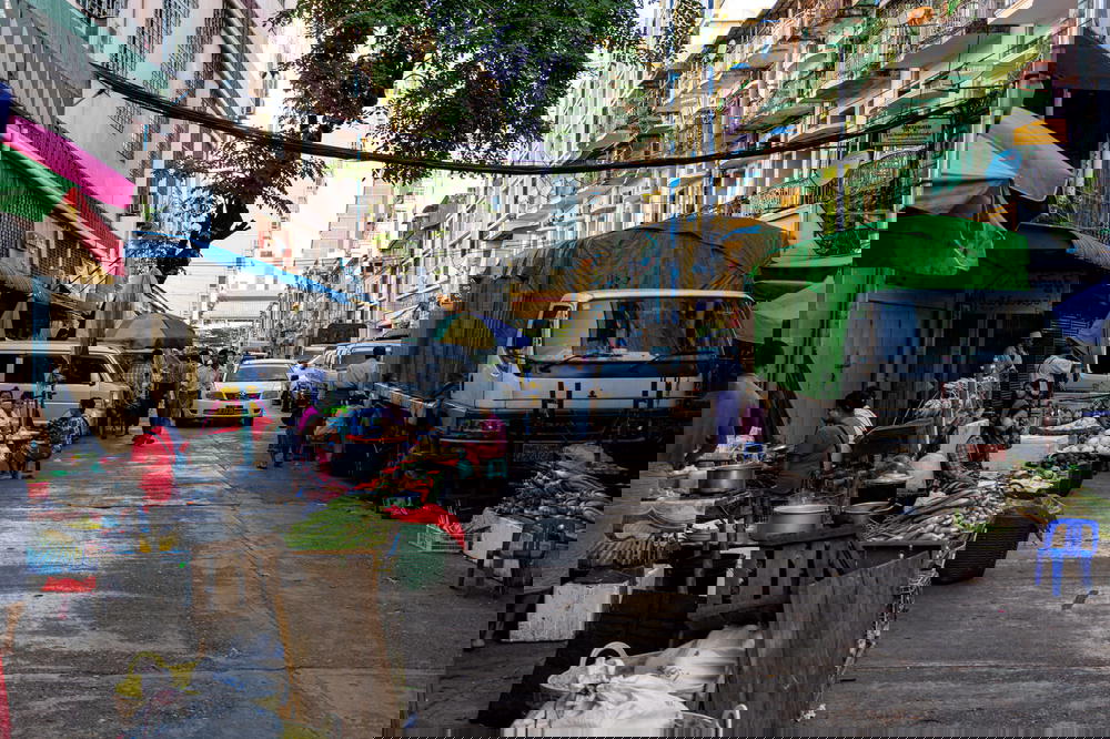 A street market on a local street with pastel colored buildings in Yangon Chinatown