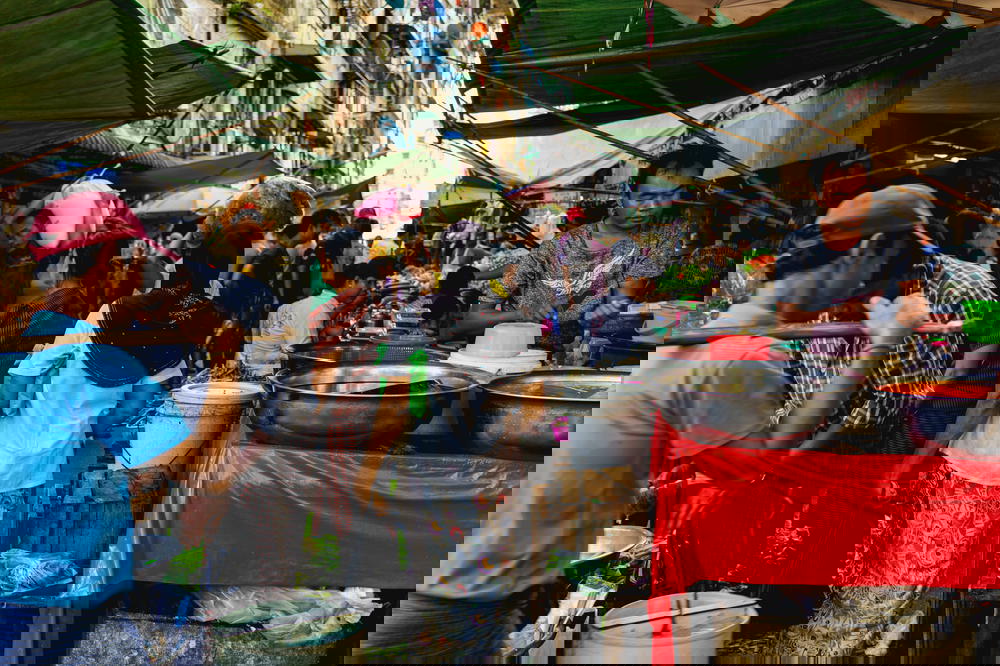 Woman carrying a bundle on her head at a busy crowded street market in Chinatown of Yangon Myanmar