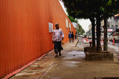 A man walking down a sidewalk in Yangon.