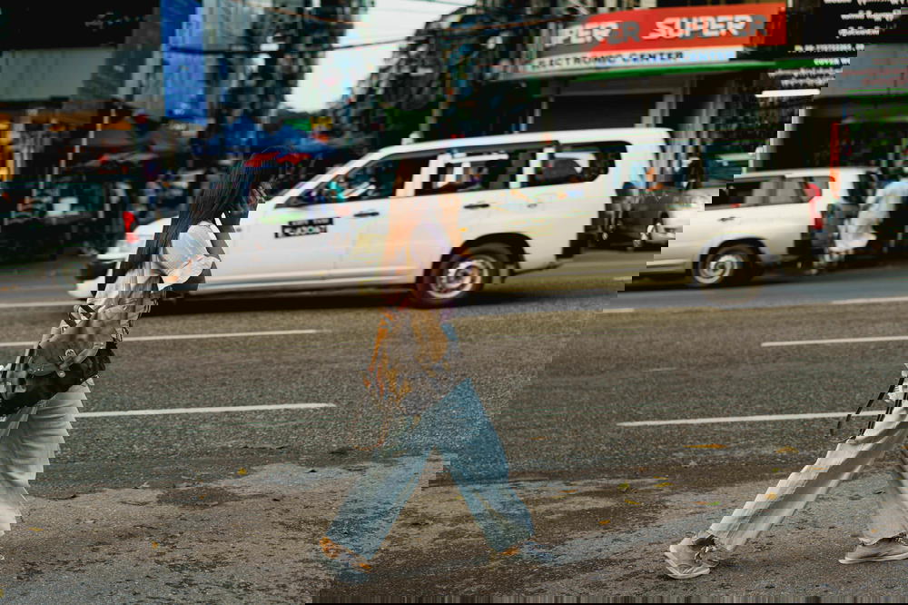 A woman walking down a city street in Yangon.