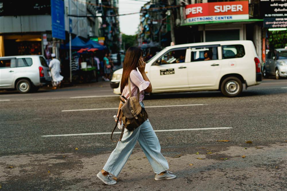 A woman walking down a city street in Yangon.