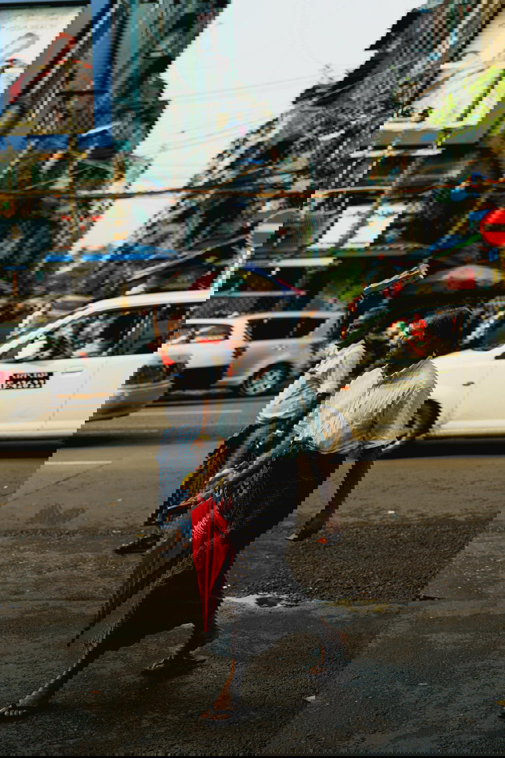 Two local Burmese men wearing traditional longyi dress on a busy street at rush hour in Yangon Myanmar