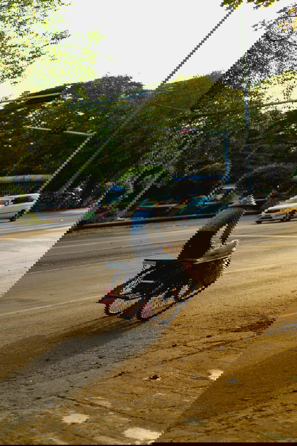 Burmese peddler riding a bicycle in downtown Yangon Myanmar wearing a traditional conical rice hat