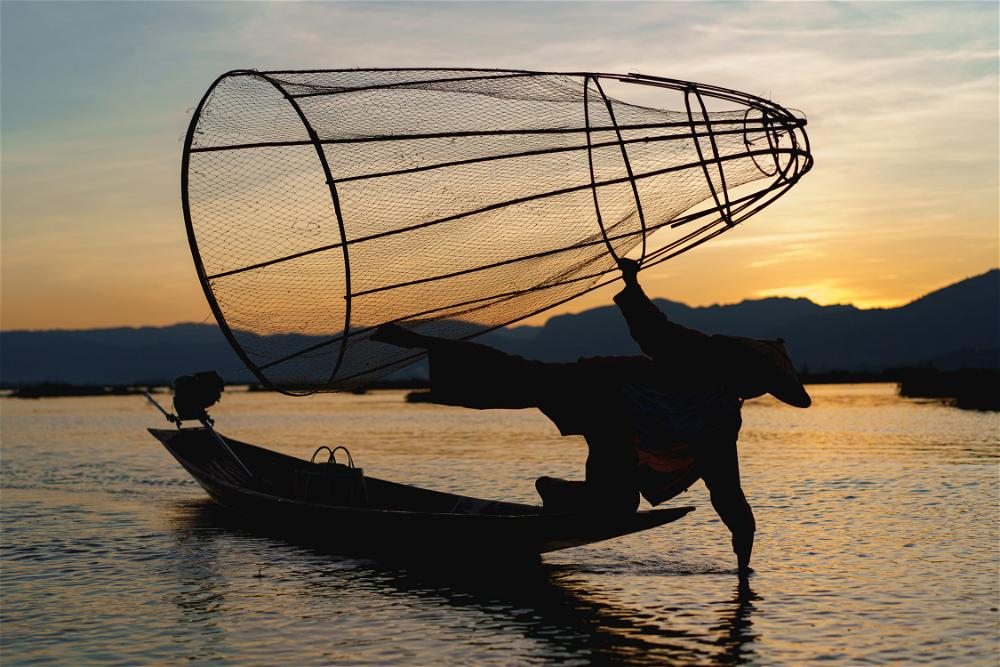 Dancing fisherman on boat in Inle Lake, Myanmar (Burma) at sunset