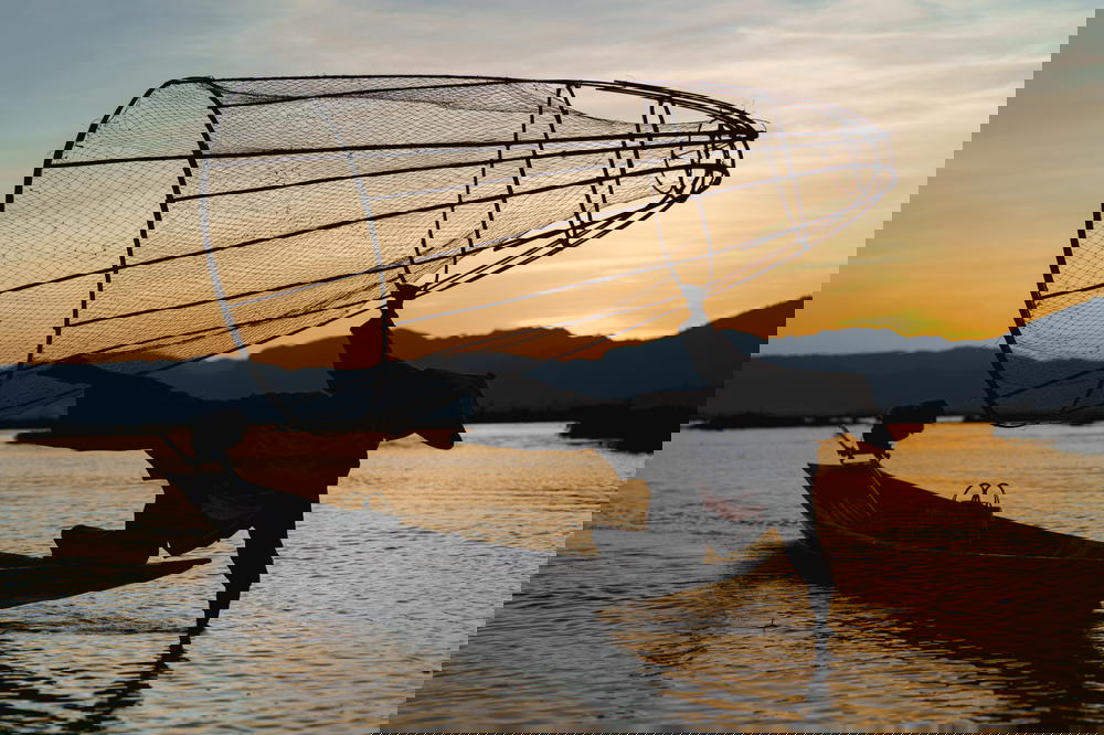 Dancing fisherman on boat in Inle Lake, Myanmar (Burma) at sunset