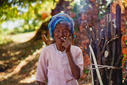 Old Burmese ethnic tribal woman smoking a cigar near Inle Lake