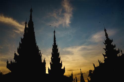 Silhouettes of Buddhist temples at Shwedagon Pagoda at golden hour sunset Yangon Myanmar Burma
