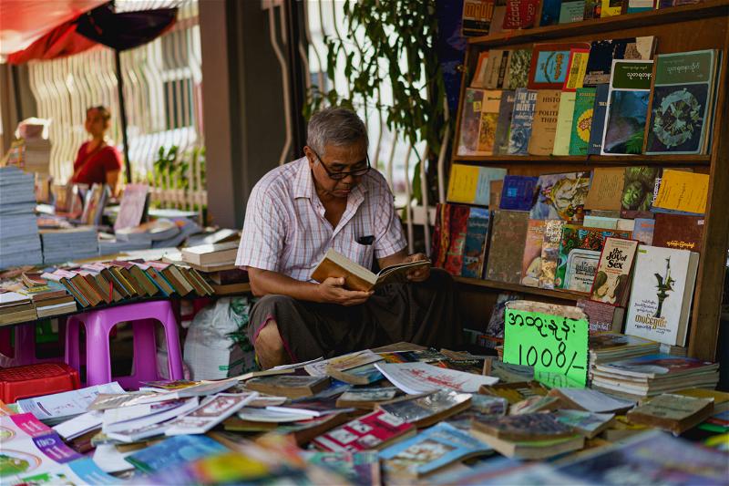 Burmese man selling books at weekend book market near Secretariat downtown Yangon Myanmar Burma