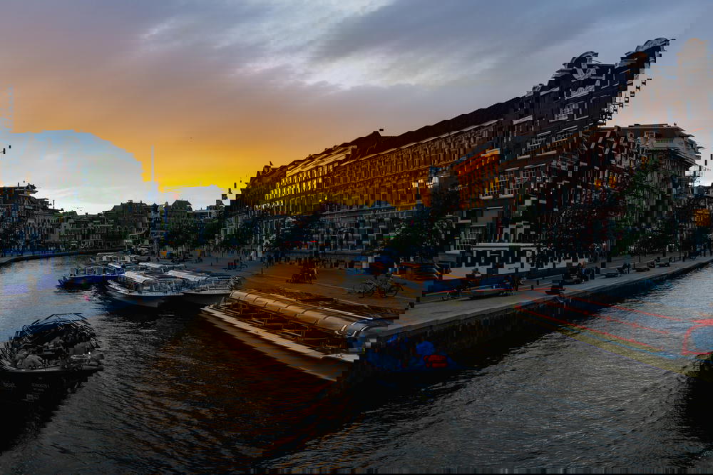 A canal in Amsterdam, The Netherlands with boats navigating through its iconic architecture.