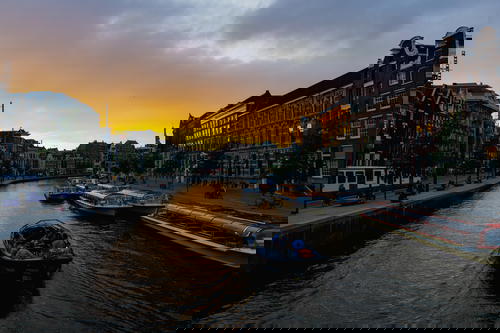 A canal in Amsterdam, The Netherlands with boats navigating through its iconic architecture.