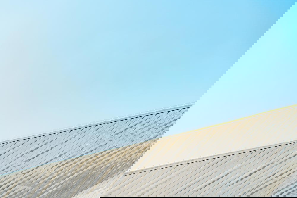 A man rides a skateboard in Rotterdam against a blue sky.