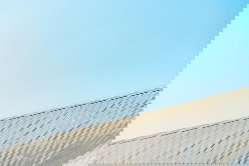 A man rides a skateboard in Rotterdam against a blue sky.