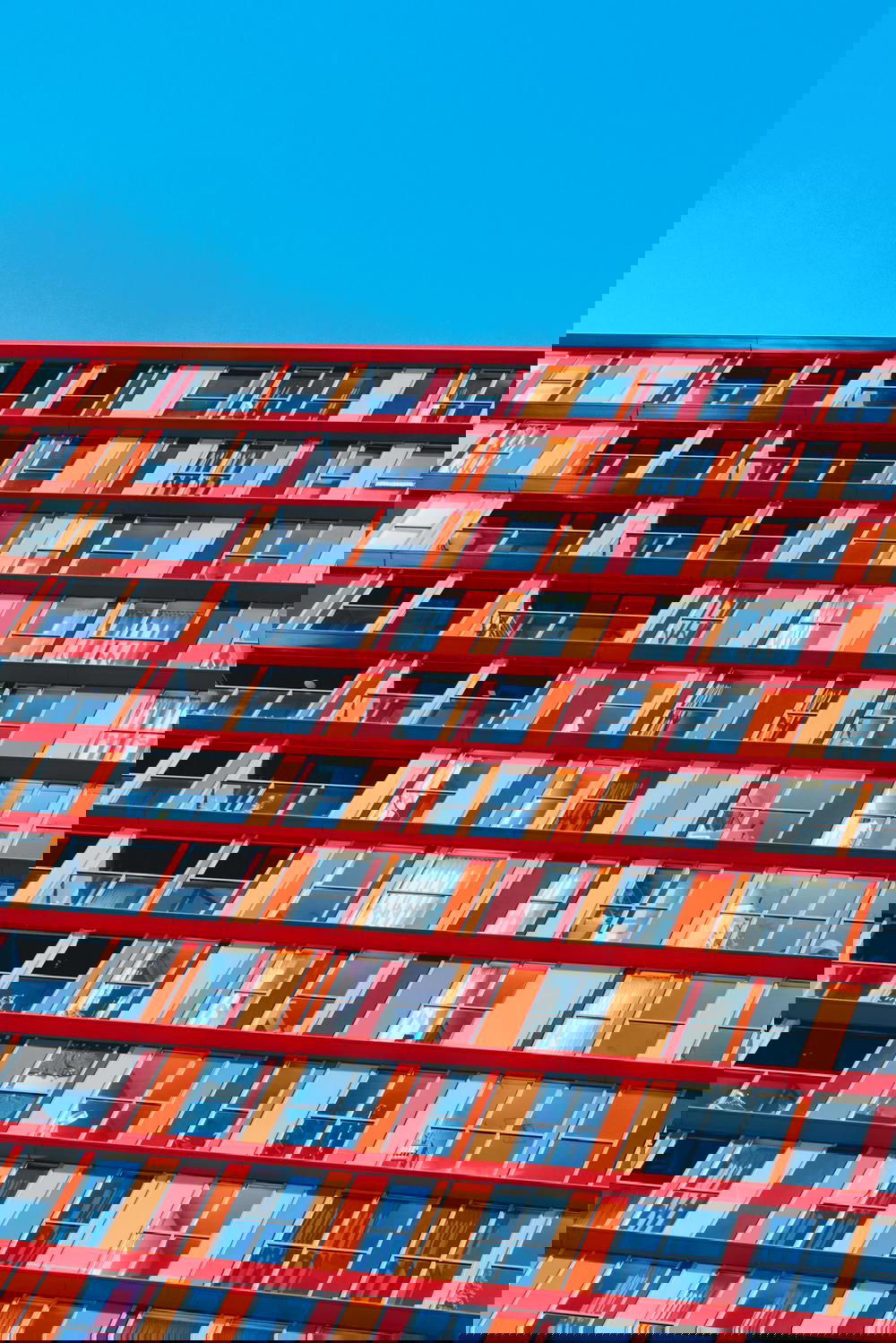 A Dutch architecture masterpiece in Rotterdam boasting numerous windows against a vibrant blue sky.