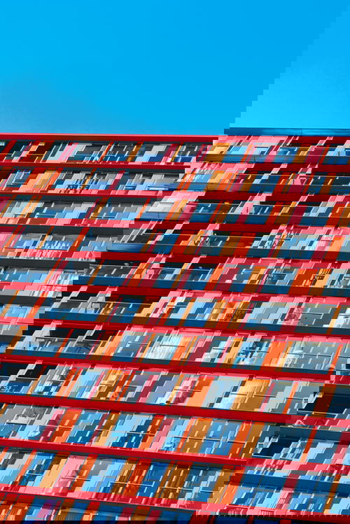 A Dutch architecture masterpiece in Rotterdam boasting numerous windows against a vibrant blue sky.