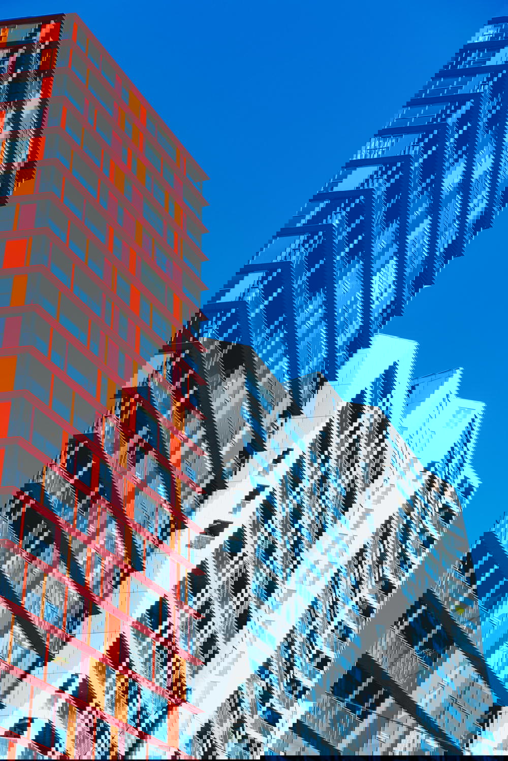 A group of modern apartment buildings in Rotterdam against a blue sky.