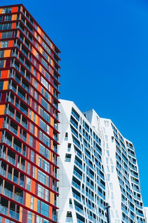A group of modern apartment buildings in Rotterdam against a blue sky.