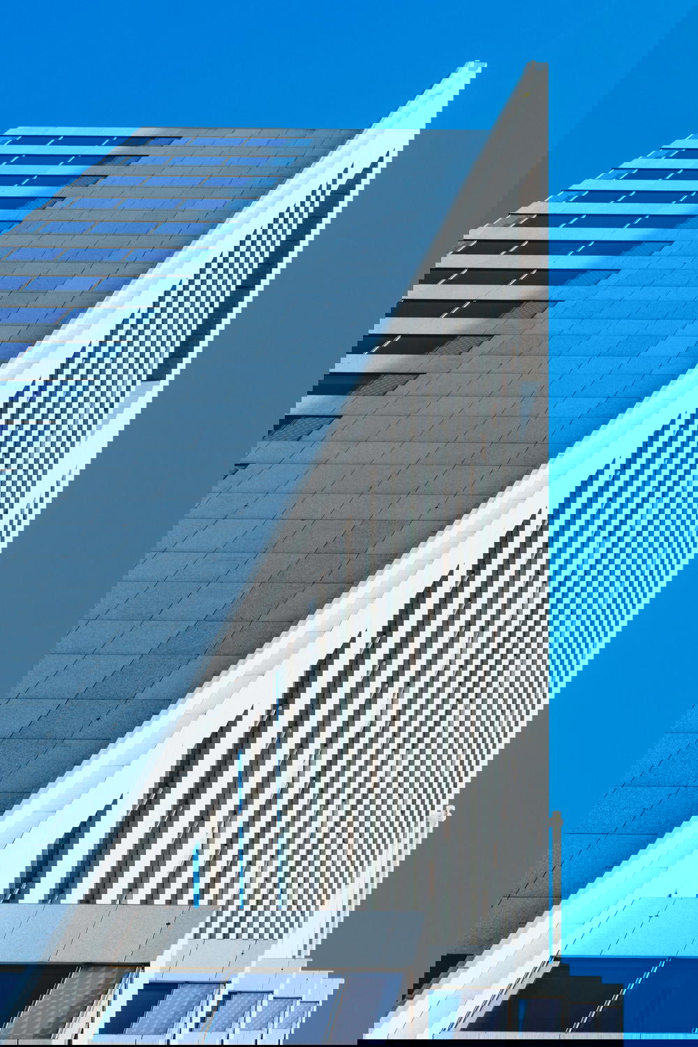 A tall architecture in Rotterdam against a blue sky.