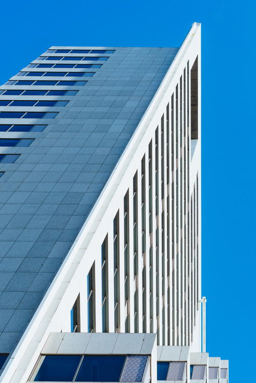 A tall architecture in Rotterdam against a blue sky.