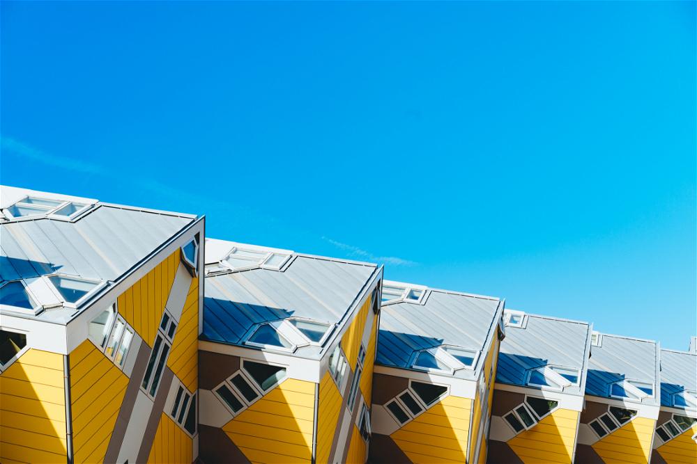 A row of yellow and white buildings showcasing Rotterdam's architecture against the backdrop of a blue sky in The Netherlands.